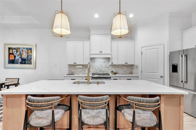 kitchen featuring hanging light fixtures, stainless steel appliances, an island with sink, and white cabinets