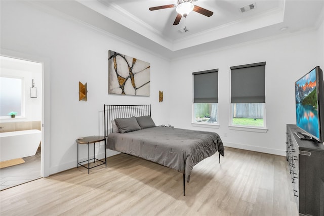 bedroom featuring connected bathroom, crown molding, light hardwood / wood-style floors, and a raised ceiling