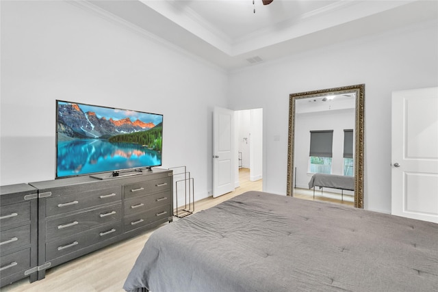 bedroom with a tray ceiling, light hardwood / wood-style flooring, ornamental molding, and ceiling fan