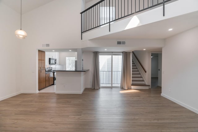 unfurnished living room with a towering ceiling and light hardwood / wood-style flooring