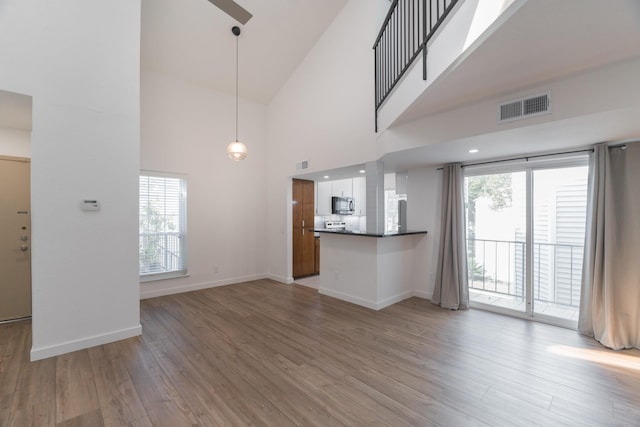 unfurnished living room with ceiling fan, high vaulted ceiling, and light hardwood / wood-style floors