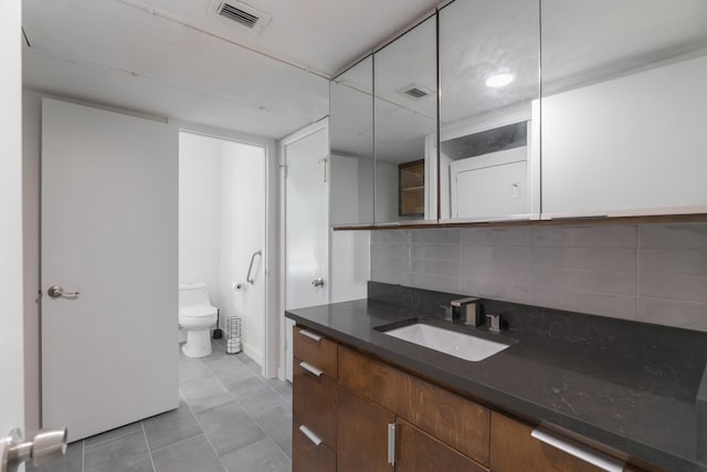 bathroom featuring vanity, backsplash, tile patterned floors, and toilet