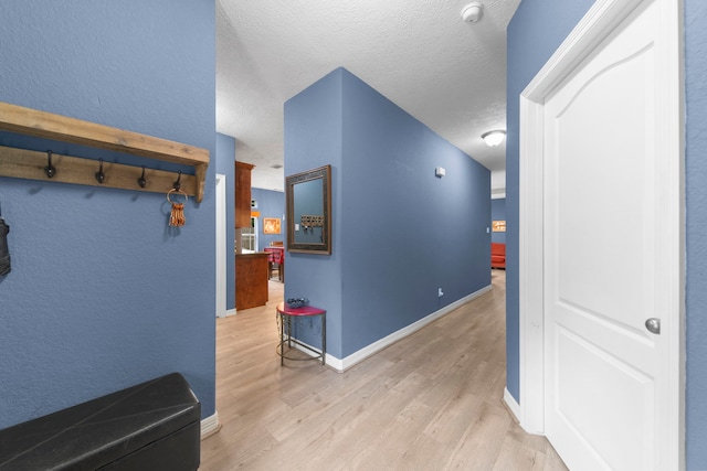 hallway with a textured ceiling and light wood-type flooring