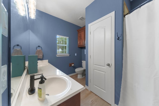 bathroom with hardwood / wood-style flooring, vanity, toilet, and a textured ceiling