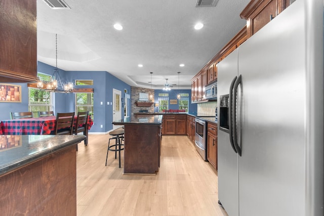 kitchen featuring pendant lighting, appliances with stainless steel finishes, a breakfast bar, and a raised ceiling