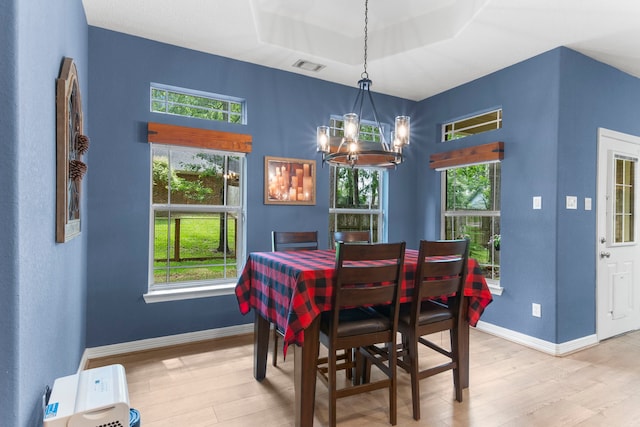 dining area with a notable chandelier, a wealth of natural light, and light wood-type flooring