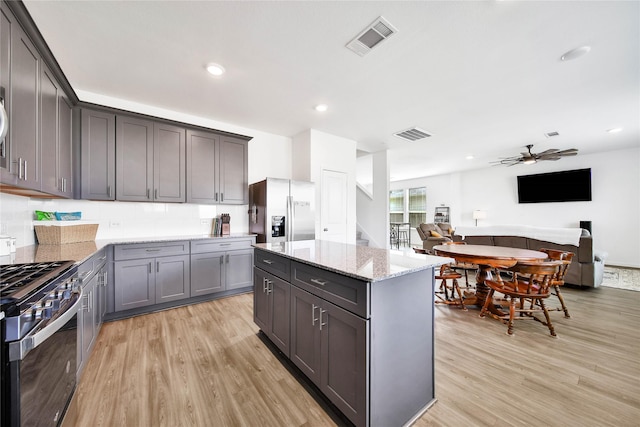 kitchen featuring stainless steel appliances, a center island, gray cabinetry, and light wood-type flooring