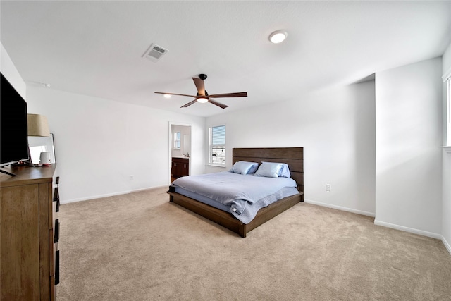 carpeted bedroom with ensuite bath and ceiling fan