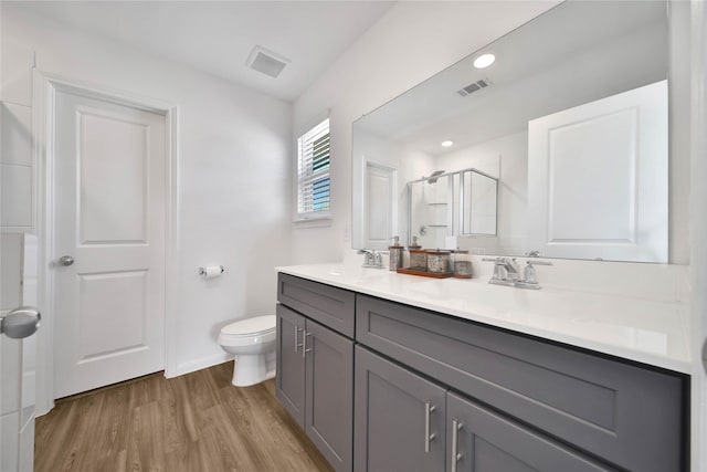 bathroom featuring vanity, toilet, an enclosed shower, and hardwood / wood-style floors