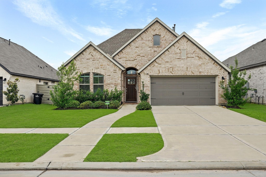 french country inspired facade featuring a garage and a front lawn