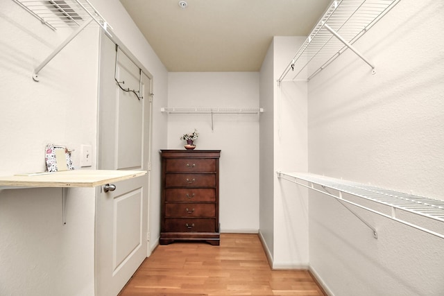 walk in closet with light hardwood / wood-style floors