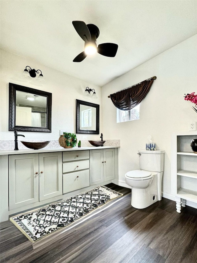 bathroom with double vanity, toilet, ceiling fan, and wood finished floors