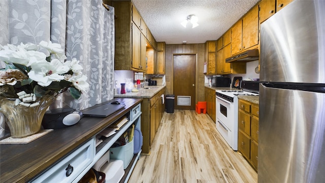 kitchen featuring stainless steel refrigerator, sink, light wood-type flooring, white range with gas cooktop, and a textured ceiling