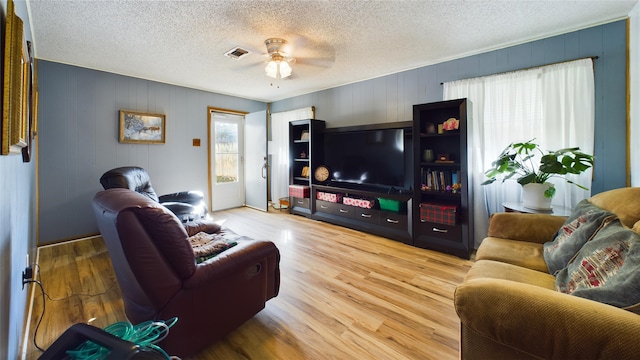 living room with hardwood / wood-style flooring, a textured ceiling, and ceiling fan