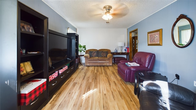 living room featuring ceiling fan, light hardwood / wood-style flooring, and a textured ceiling