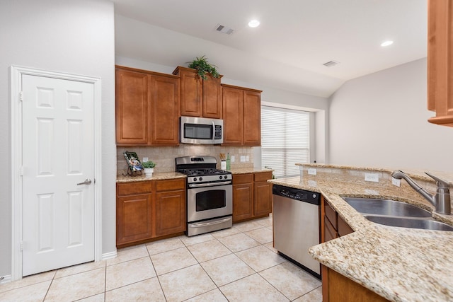 kitchen featuring sink, decorative backsplash, light tile patterned floors, light stone counters, and stainless steel appliances