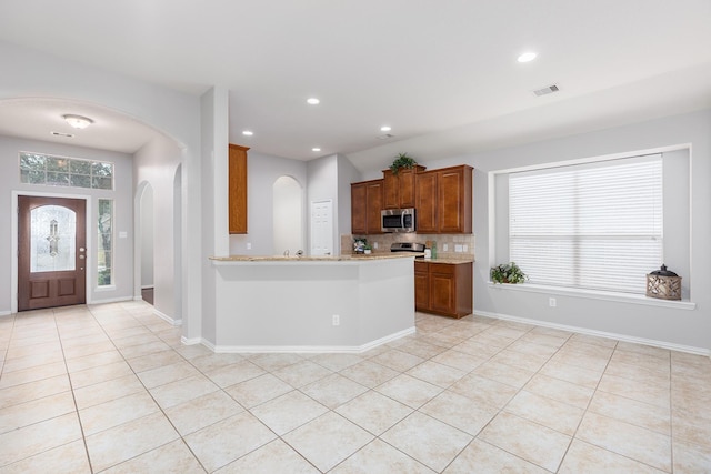 kitchen featuring tasteful backsplash, light tile patterned floors, and kitchen peninsula