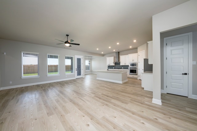 unfurnished living room with sink, ceiling fan, and light hardwood / wood-style flooring