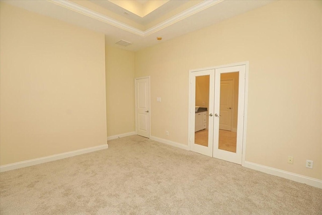 carpeted spare room with french doors, ornamental molding, and a tray ceiling