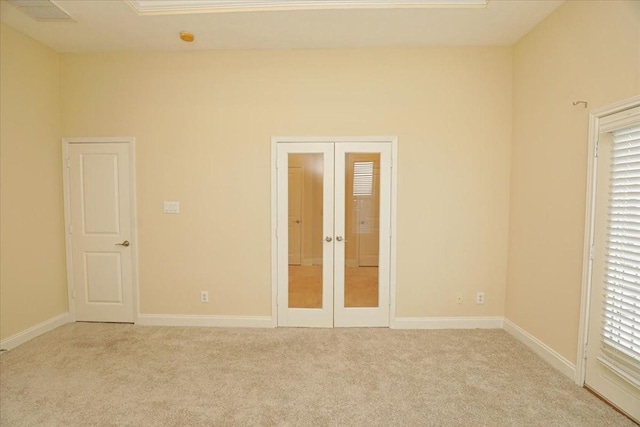 unfurnished bedroom featuring french doors, multiple windows, and light carpet