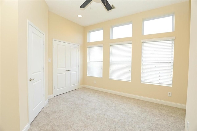 unfurnished room with light colored carpet and ceiling fan