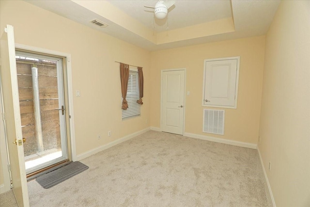 carpeted empty room with a tray ceiling and ceiling fan