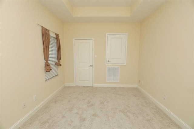 carpeted spare room with a tray ceiling