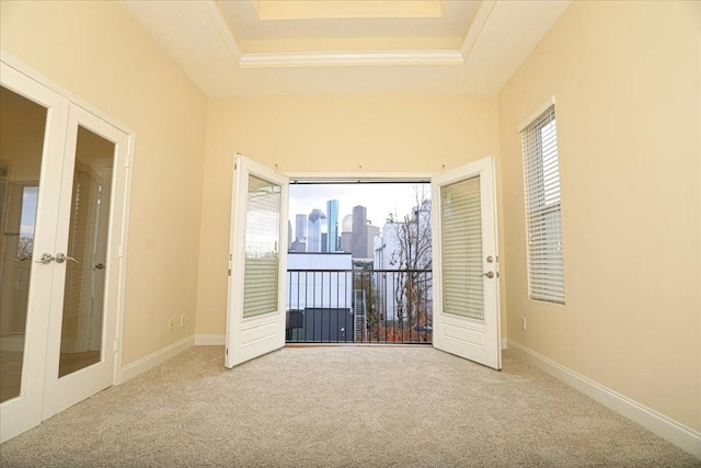 carpeted spare room featuring a raised ceiling and french doors