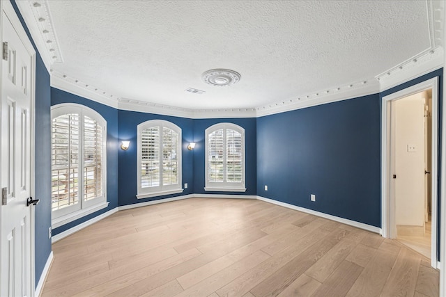 spare room featuring ornamental molding, light hardwood / wood-style floors, and a textured ceiling