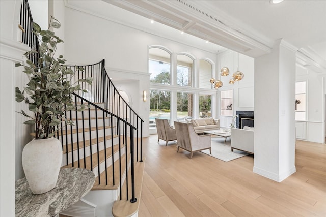 stairs with hardwood / wood-style floors, a fireplace, ornamental molding, and a high ceiling