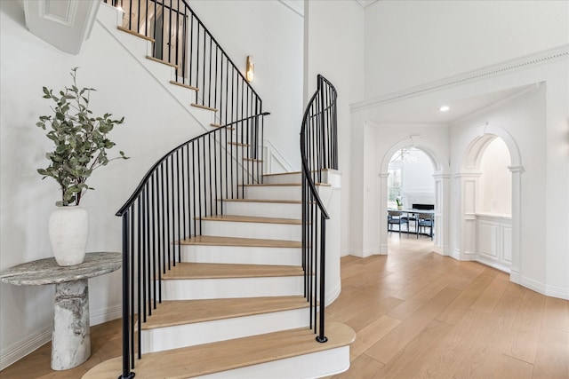 staircase featuring wood-type flooring and a high ceiling