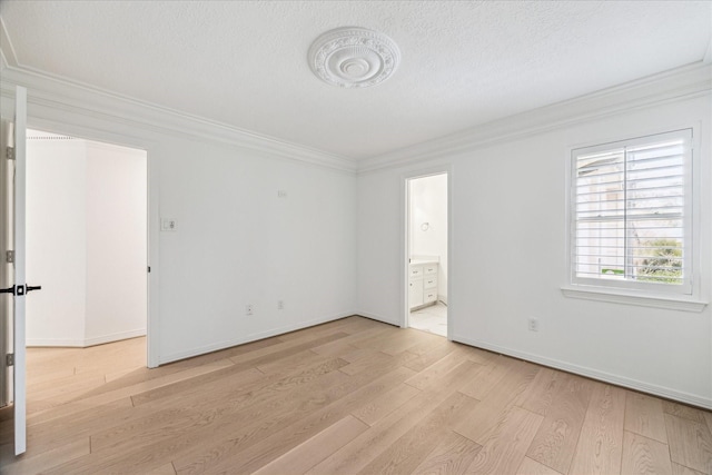 empty room featuring crown molding, a textured ceiling, and light wood-type flooring