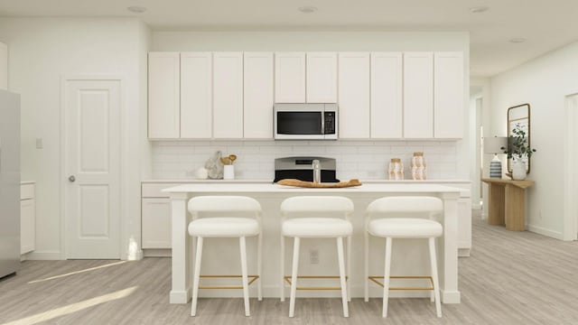 kitchen with backsplash, white appliances, an island with sink, and white cabinets