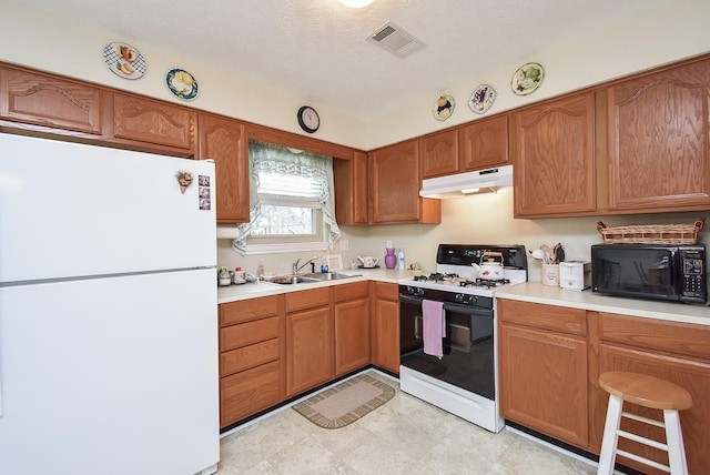 11943 Fawnview Dr, Houston, TX 77070 - kitchen with freestanding refrigerator, gas stove, under cabinet range hood, black microwave, and a sink