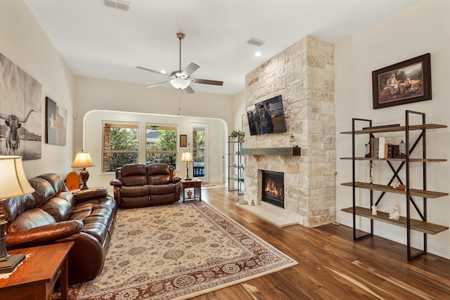 living room featuring dark hardwood / wood-style flooring, a fireplace, and ceiling fan