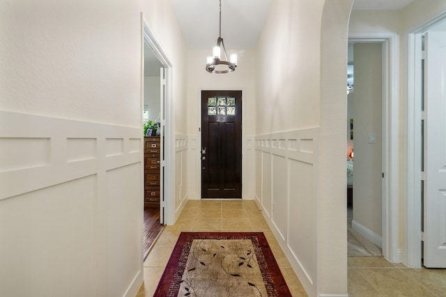 tiled foyer with a notable chandelier