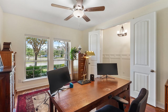 office space with wood-type flooring and ceiling fan with notable chandelier