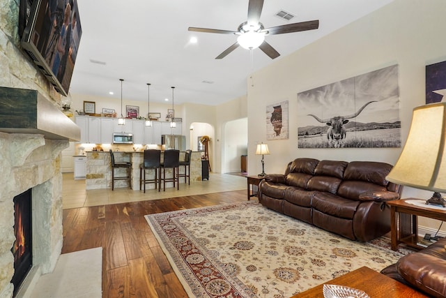 living room with a premium fireplace, wood-type flooring, and ceiling fan