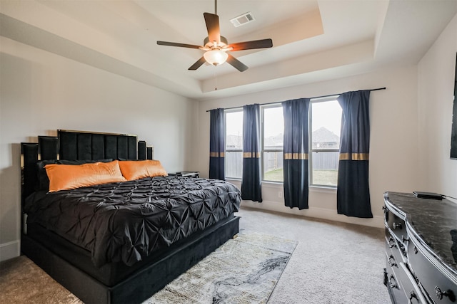 bedroom with ceiling fan, light colored carpet, and a raised ceiling