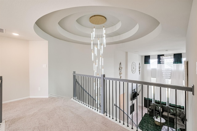 hall featuring a tray ceiling and carpet floors