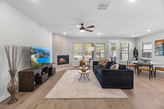 living room with ceiling fan, a fireplace, and light wood-type flooring