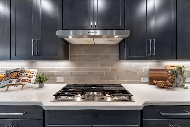 kitchen featuring stainless steel gas stovetop, light stone countertops, and backsplash