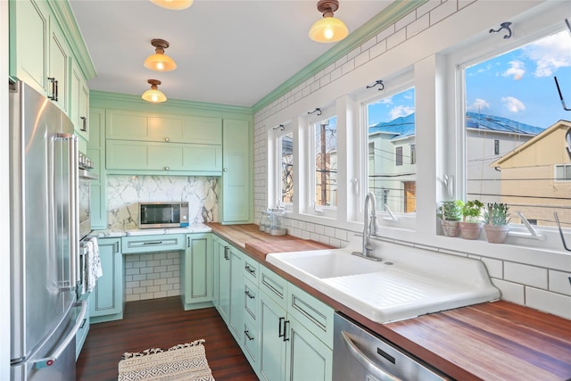 kitchen with dark wood-type flooring, green cabinets, appliances with stainless steel finishes, and butcher block countertops