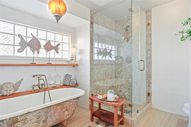 bathroom with hardwood / wood-style flooring, separate shower and tub, a wealth of natural light, and tile walls