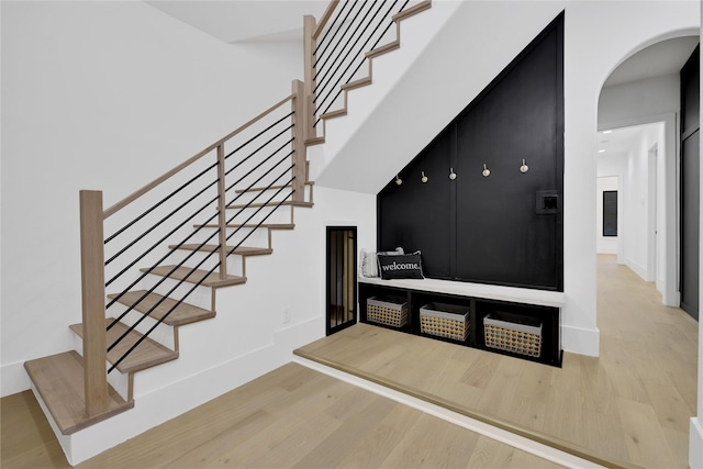 stairs with baseboards, arched walkways, and wood finished floors