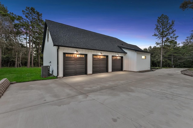 garage at dusk featuring a yard and central air condition unit