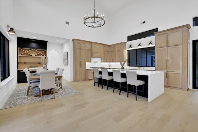 kitchen featuring light wood-style floors, a kitchen island, light countertops, and a notable chandelier