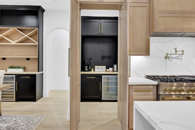 kitchen with tasteful backsplash, wine cooler, range with two ovens, and light wood-style flooring