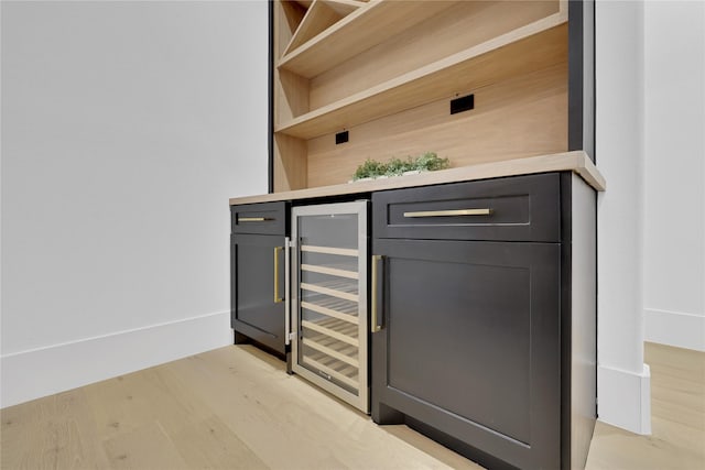 bar featuring a bar, light wood-style floors, and beverage cooler