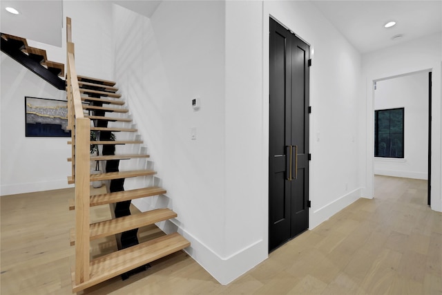 stairway featuring baseboards, wood finished floors, and recessed lighting